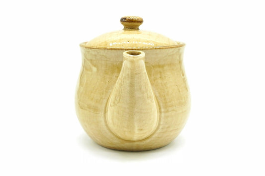 Hanabira Kyusu seen from the spout end, the straw-beige body behind the spout and the lid with its amber knob on top