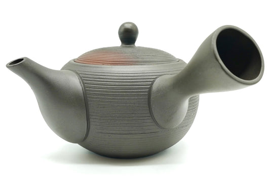 Hinode Kyusu side view, a dark charcoal Tokoname teapot with fine ridges around the body, a side handle and a red rim showing at the lid