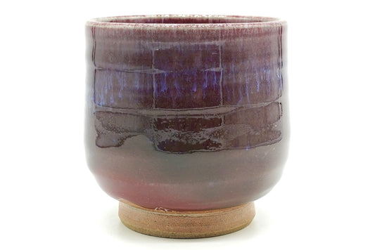 Shinsha-Nagashi Yunomi, an Arita ware teacup in a flowing copper-red glaze shading from deep wine to violet, with a bare sandy foot