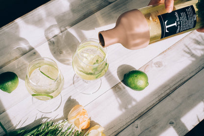 Pouring cold-brewed tea from a HARIO Filter-in Bottle 750ml smoky pink into glasses with lime on a sunny table
