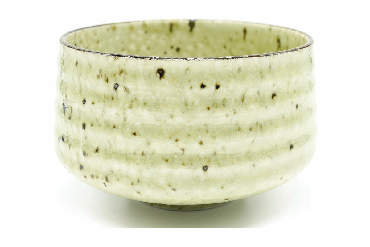 Aki Chawan, a Mino ware matcha bowl in a pale yellow-green glaze flecked with dark brown over throwing ridges, front view