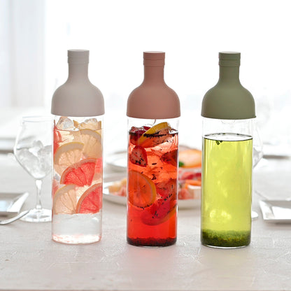 Three HARIO Filter-in Bottles 750ml in white, smoky pink and smoky green on a table, filled with fruit teas and cold-brewed sencha