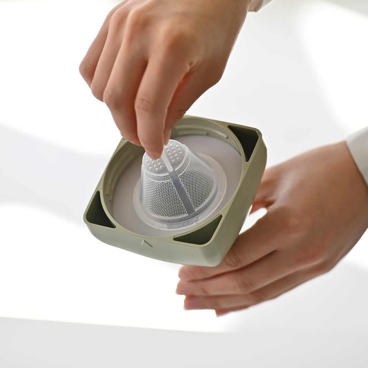 Lifting the removable mesh filter out of the smoky green cap of a HARIO Ka-Ku Bottle