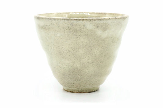 Daikon Yunomi, a speckled cream Mino ware teacup with gently dimpled sides and a wide rim, front view
