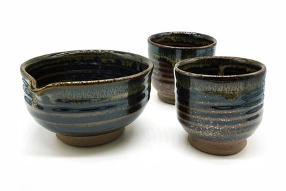 Ginga Japanese Tea Set: the black spouted matcha bowl with a band of olive and cream speckles beside its two matching cups