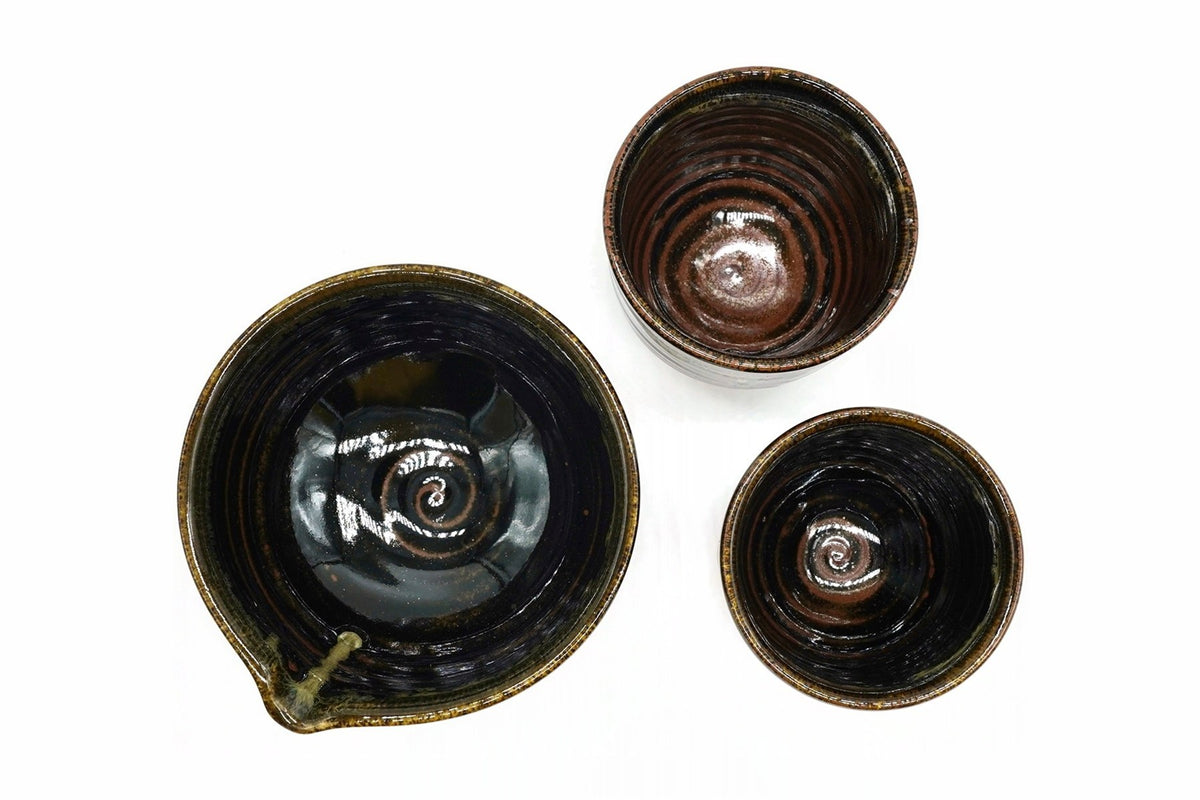 Ginga Japanese Tea Set from above, the spouted bowl and the two cups, glossy black inside with a rust-brown swirl at the centre