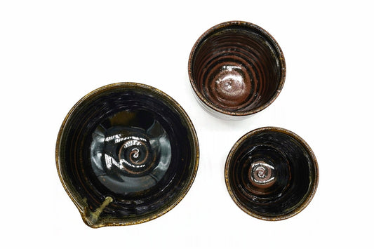 Ginga Japanese Tea Set from above, the spouted bowl and the two cups, glossy black inside with a rust-brown swirl at the centre
