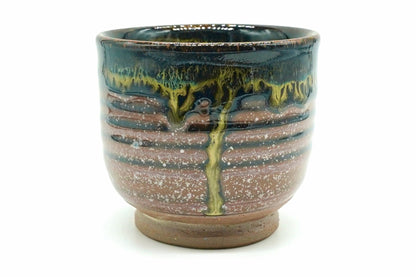Ginga Yunomi, an upright Hasami ware teacup, glossy black at the top with olive-gold drips over a warm brown body flecked with white, on a bare brown clay foot