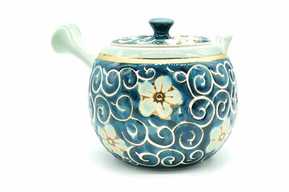 Hana-Karakusa Kyusu with the side handle on the left, a pale flower with a gold-coloured centre and white scrolls on the blue body, and a thin gold-coloured band