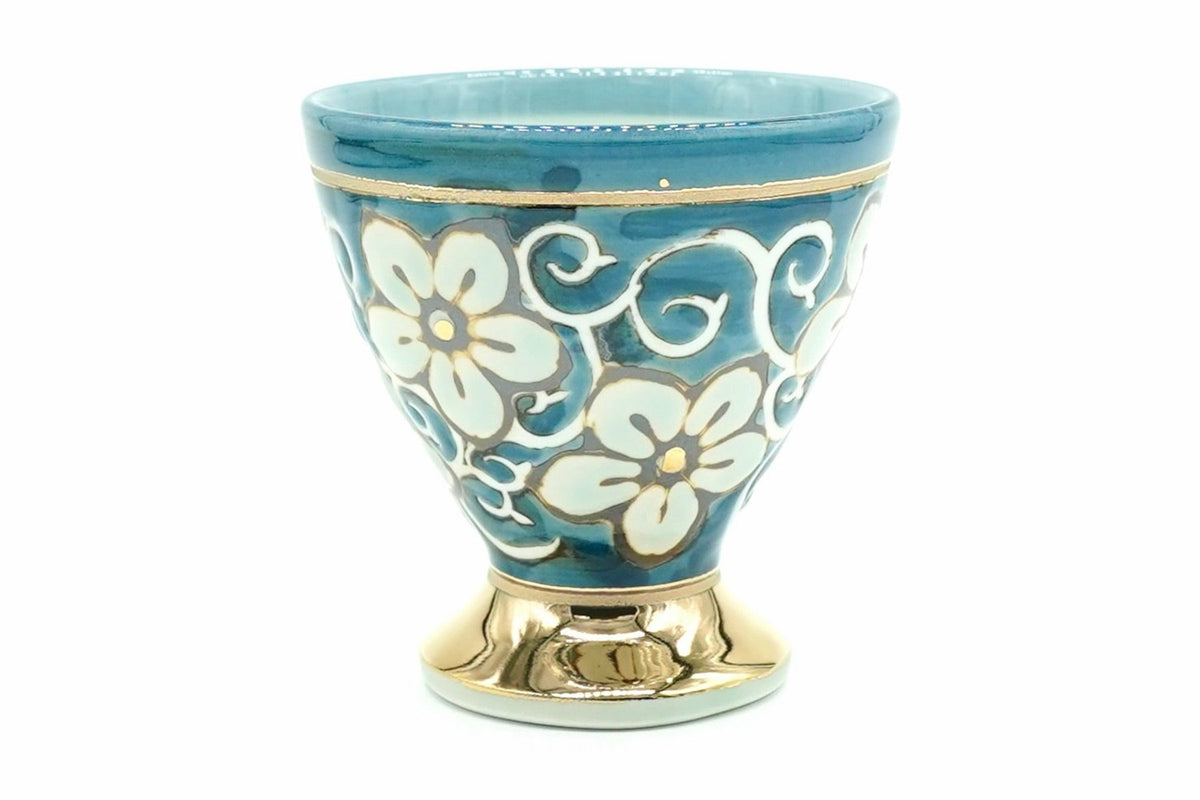 Hana-Karakusa Yunomi, a footed teacup in blue with white flowers and scrolls and a gold-coloured foot