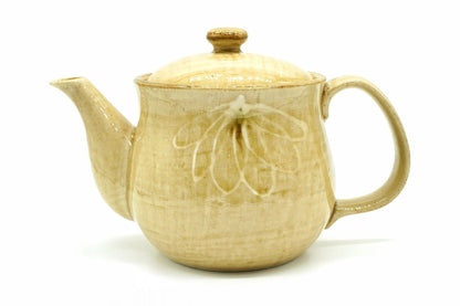Hanabira Kyusu, a Mino ware teapot in straw-beige glaze with a raised white flower of long, narrow petals on the body, a knob on the lid and the handle at the back