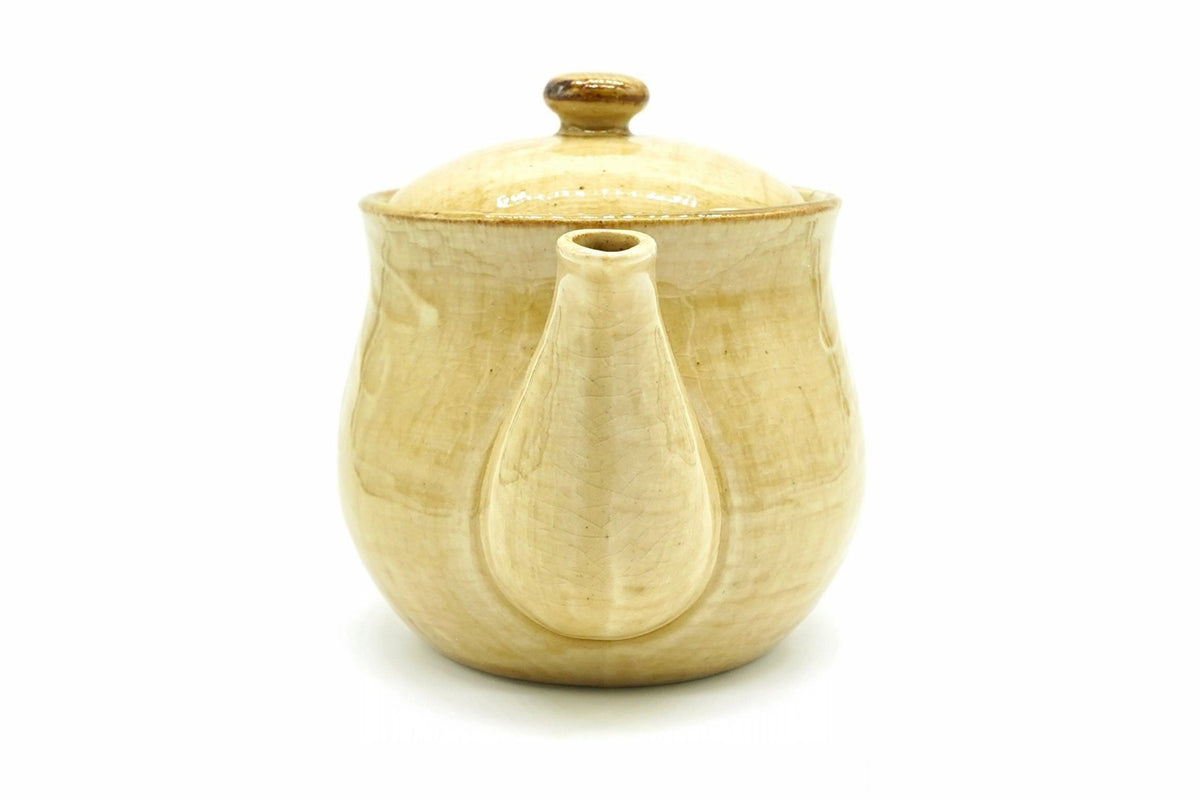 Hanabira Kyusu seen from the spout end, the straw-beige body behind the spout and the lid with its amber knob on top