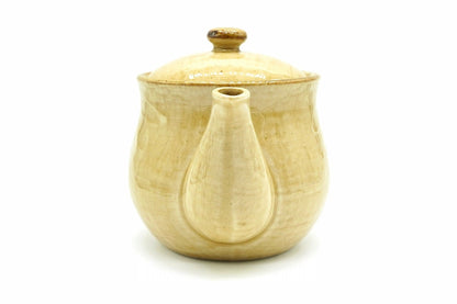 Hanabira Kyusu seen from the spout end, the straw-beige body behind the spout and the lid with its amber knob on top