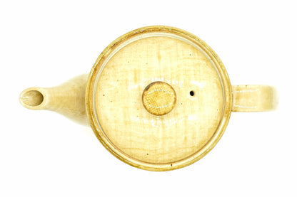 Hanabira Kyusu from above with the lid on, the round straw-beige lid and its amber knob between the spout and the handle