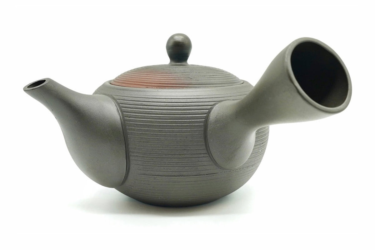 Hinode Kyusu side view, a dark charcoal Tokoname teapot with fine ridges around the body, a side handle and a red rim showing at the lid