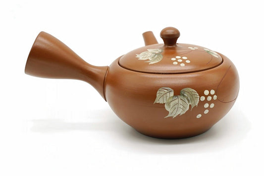 Kibana Kyusu, an orange-red clay Tokoname teapot painted with pale leaves and clusters of white berries, side view