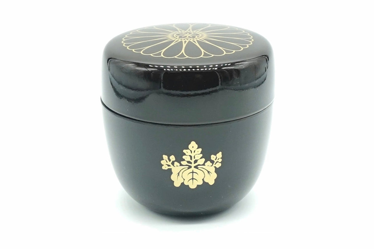 Kikumon Natsume in black, a glossy matcha caddy with a large gold chrysanthemum on the lid and a gold paulownia crest on the body