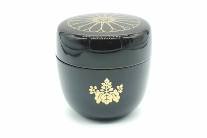 Kikumon Natsume in black, a glossy matcha caddy with a large gold chrysanthemum on the lid and a gold paulownia crest on the body