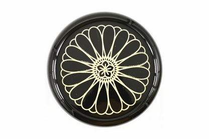 Lid of the black Kikumon Natsume from above, filled by one large gold chrysanthemum crest