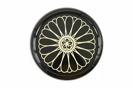Lid of the black Kikumon Natsume from above, filled by one large gold chrysanthemum crest