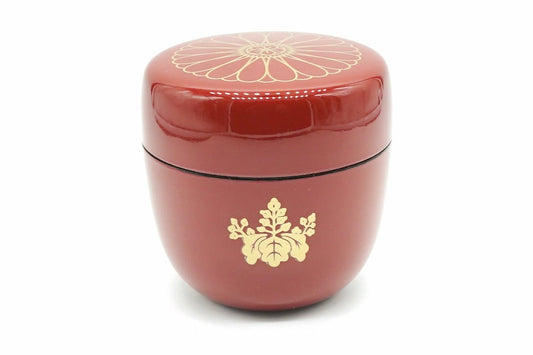 Kikumon Natsume in red, a glossy matcha caddy with a large gold chrysanthemum on the lid and a gold paulownia crest on the body