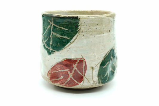 Kōyō Yunomi, a speckled cream Mino ware teacup hand-painted with green and red leaves, front view