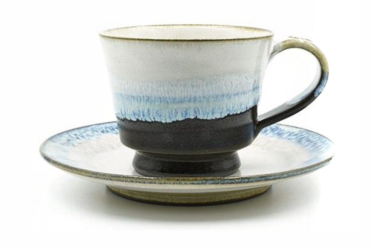 Kujira Yunomi, a white Mino ware cup and saucer with blue glaze dripping over a black foot, front view
