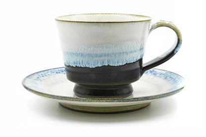 Kujira Yunomi, a white Mino ware cup and saucer with blue glaze dripping over a black foot, front view