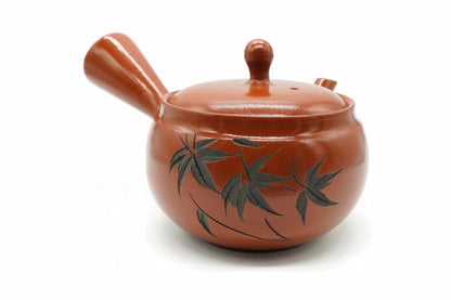 Sasa Kyusu, a glossy red-orange teapot painted with dark bamboo leaves, side view