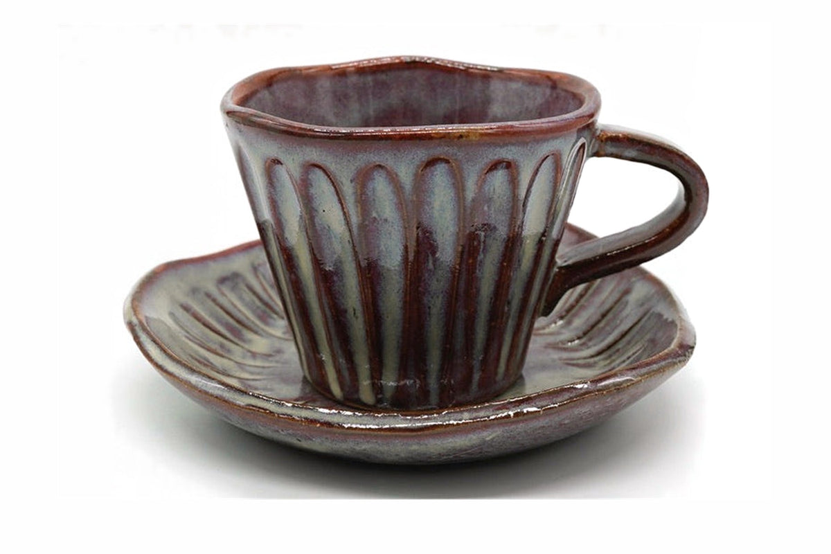 Shibu Yunomi, a fluted Mino ware cup with a handle in a mottled purple-brown and grey-blue glaze, on its saucer