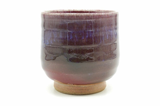 Shinsha-Nagashi Yunomi, an Arita ware teacup in a flowing copper-red glaze shading from deep wine to violet, with a bare sandy foot