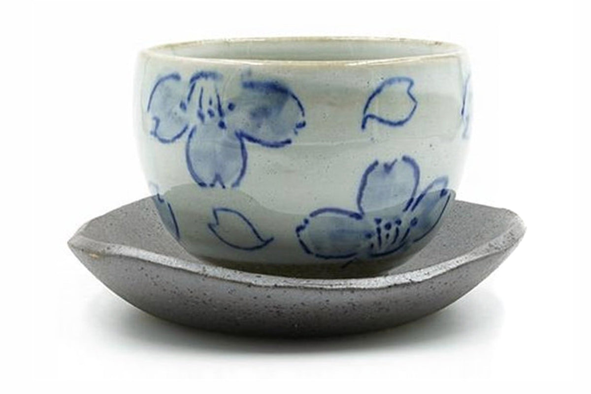 Showa Yunomi, a pale grey Mino ware cup painted with blue blossoms, sitting on a dark brown boat-shaped saucer