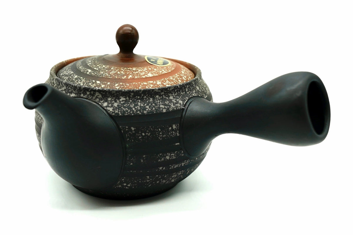 Tonbo Kyusu seen from the side, the black flank and speckled lid with a copper-brown knob