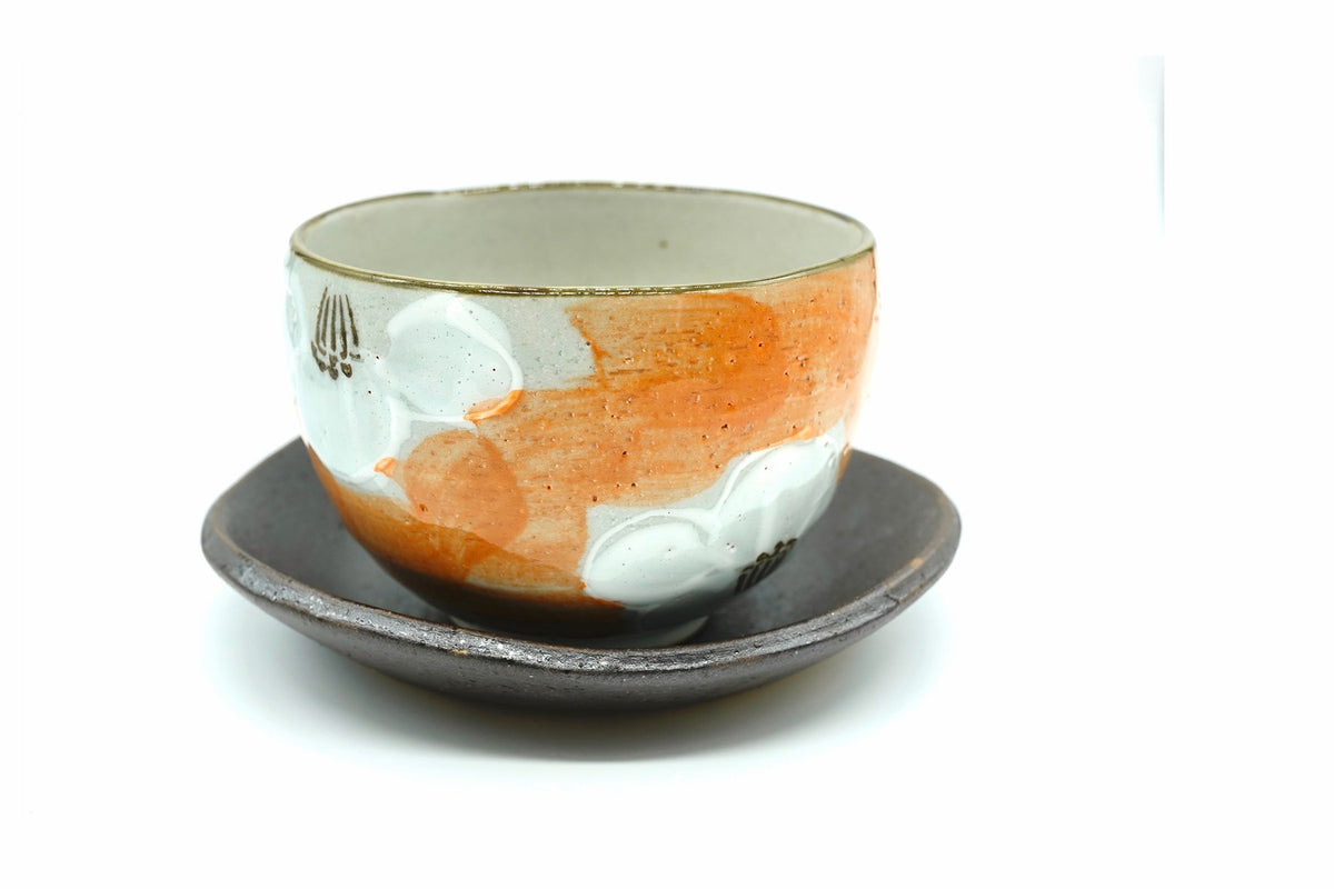 Tsubaki Yunomi, a Mino ware cup painted with white camellias over orange washes, on a dark brown saucer