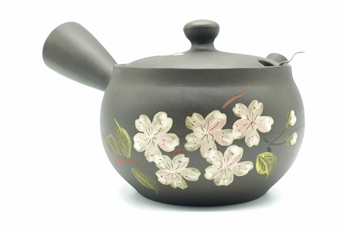 Yamazakura Kyusu, a dark charcoal Tokoname teapot with white and pale pink cherry blossoms and green leaves on the front, side handle on the left